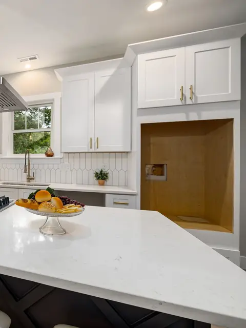 White shaker kitchen cabinets with brass pulls above a white stone island
